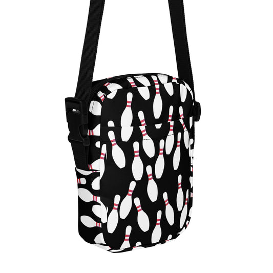 Black crossbody bag with white bowling pin pattern and adjustable black strap.