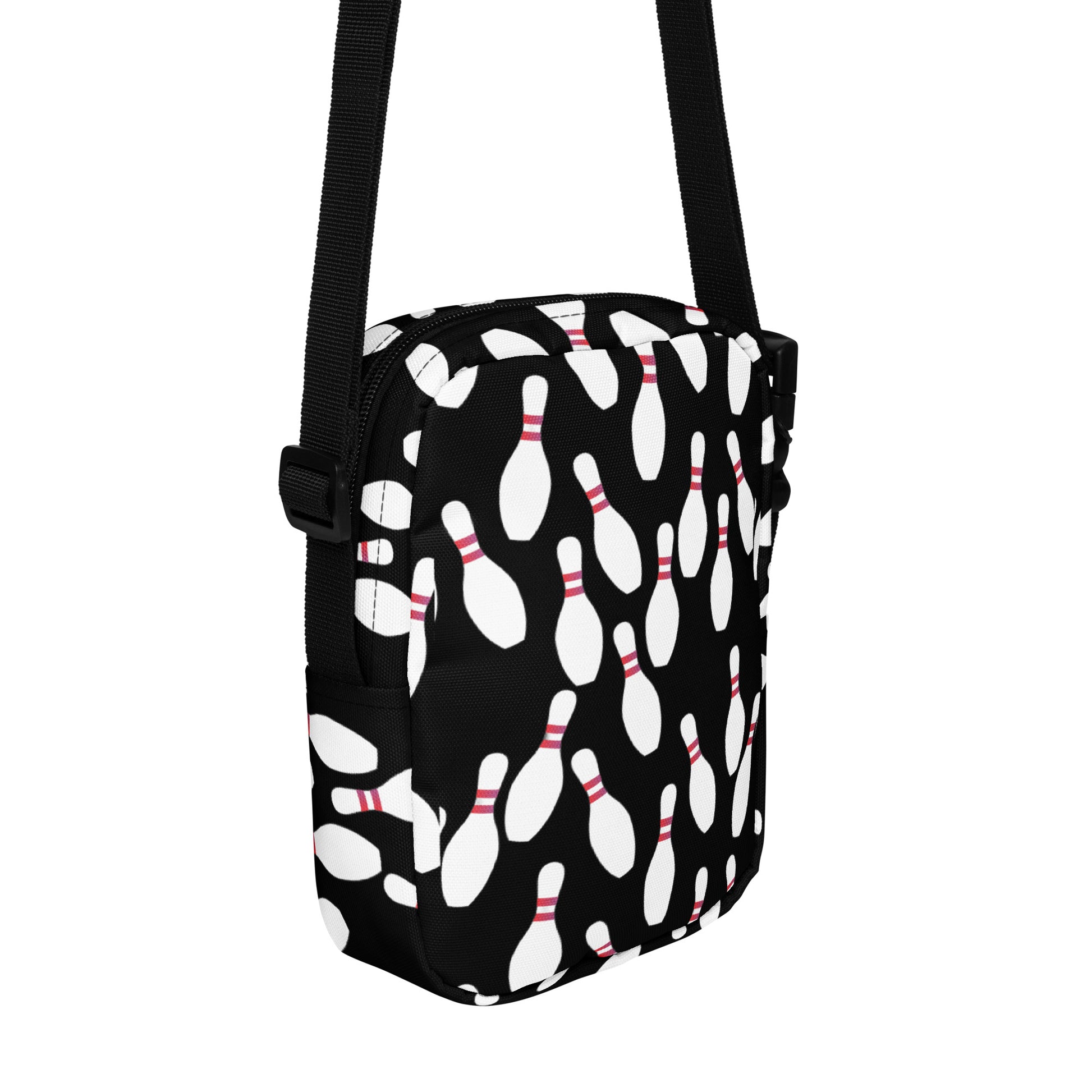 Black crossbody bag with white bowling pin pattern and adjustable strap.