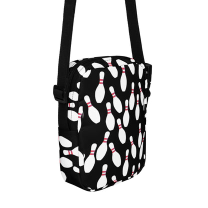 Black crossbody bag with white bowling pin pattern and adjustable strap.