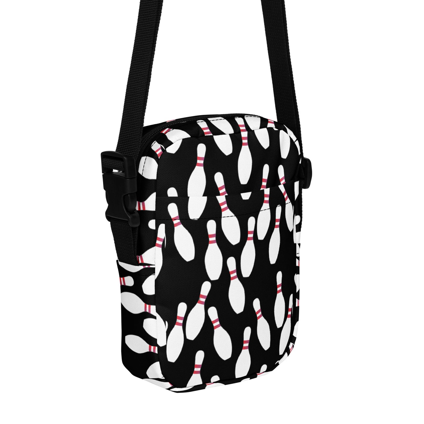 Black crossbody bag with white bowling pin pattern and adjustable black strap.