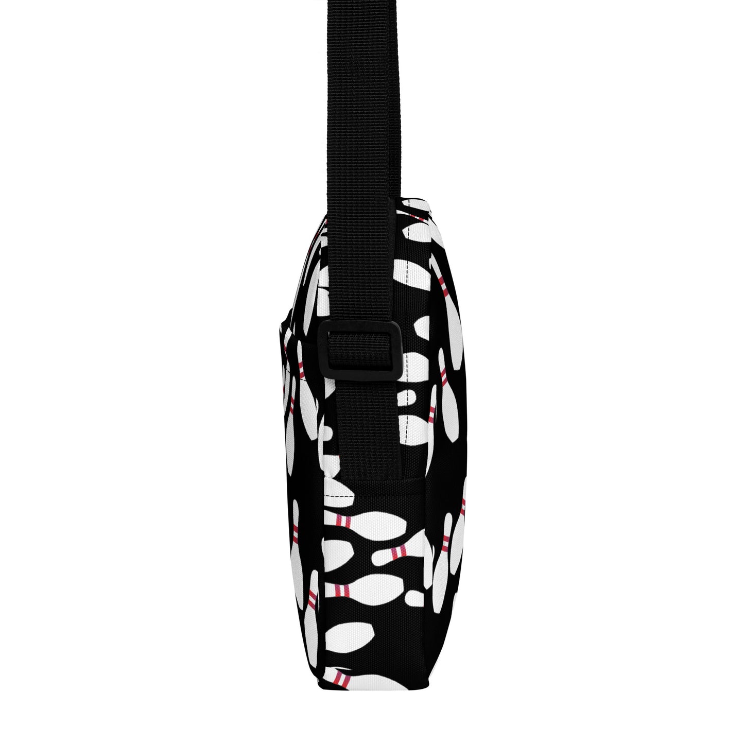 Slim black crossbody bag with white bowling pin pattern and adjustable strap.