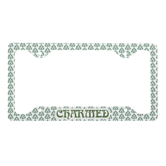 White metal license plate frame with green Celtic knot pattern and "CHARMED" lettering at bottom center.